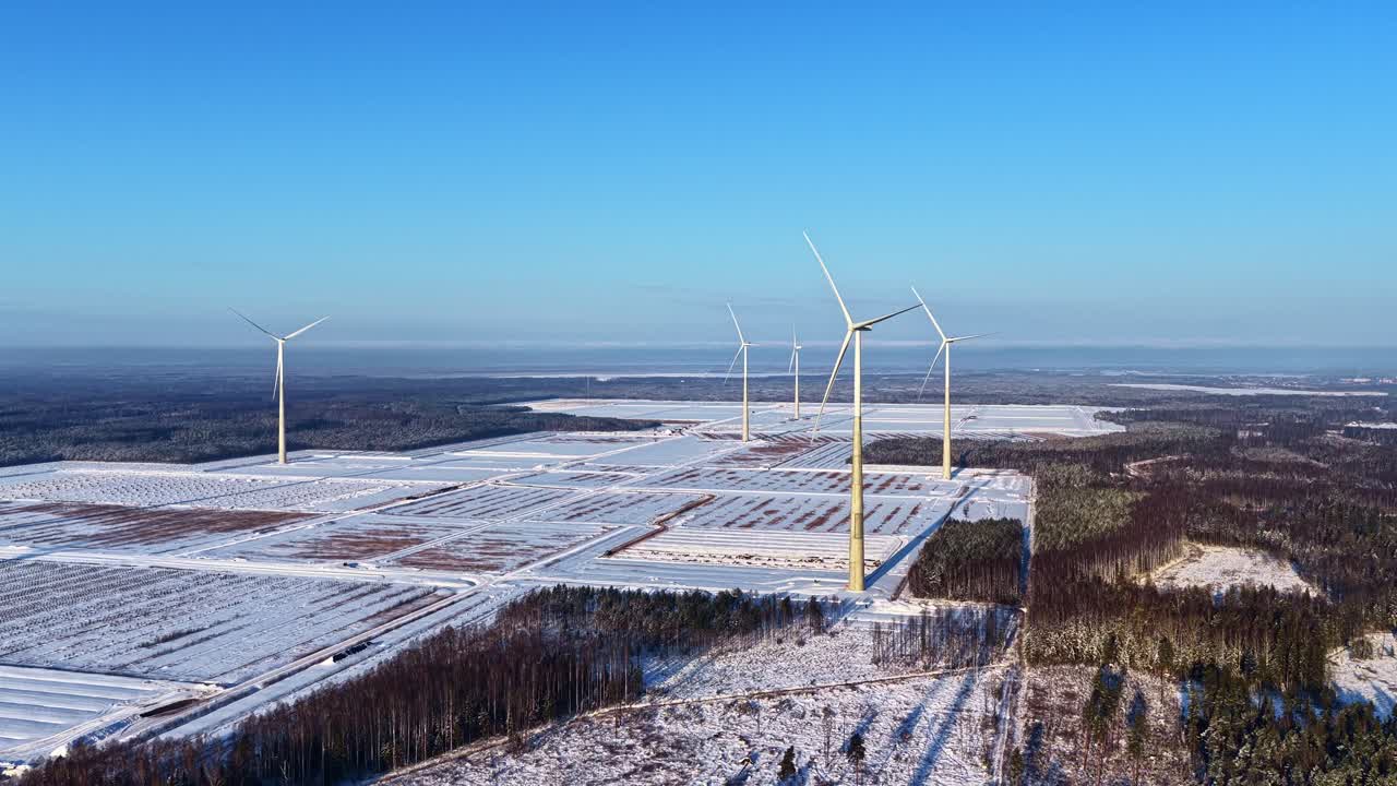 Aerial view of wind turbines in a winter landscape under a blue sky