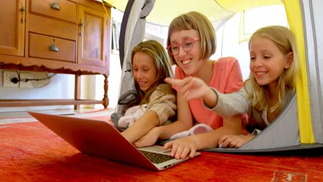 Siblings using laptop in a tent at home 4k