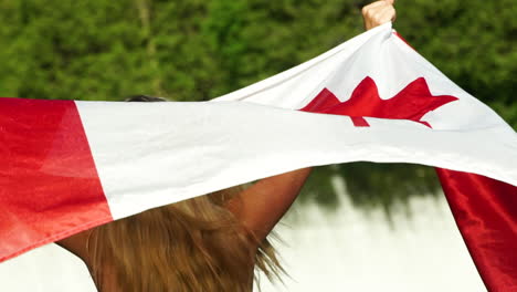 Hermosa-Joven-Posa-Orgullosamente-Con-La-Bandera-Canadiense-Mientras-Está-De-Pie-En-Un-Río