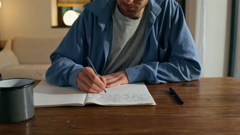 man writing in a notebook at home