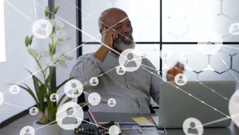 animation of network of profile icons over african american man talking on smartphone at office