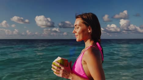 mujer disfrutando de un coco en una playa tropical