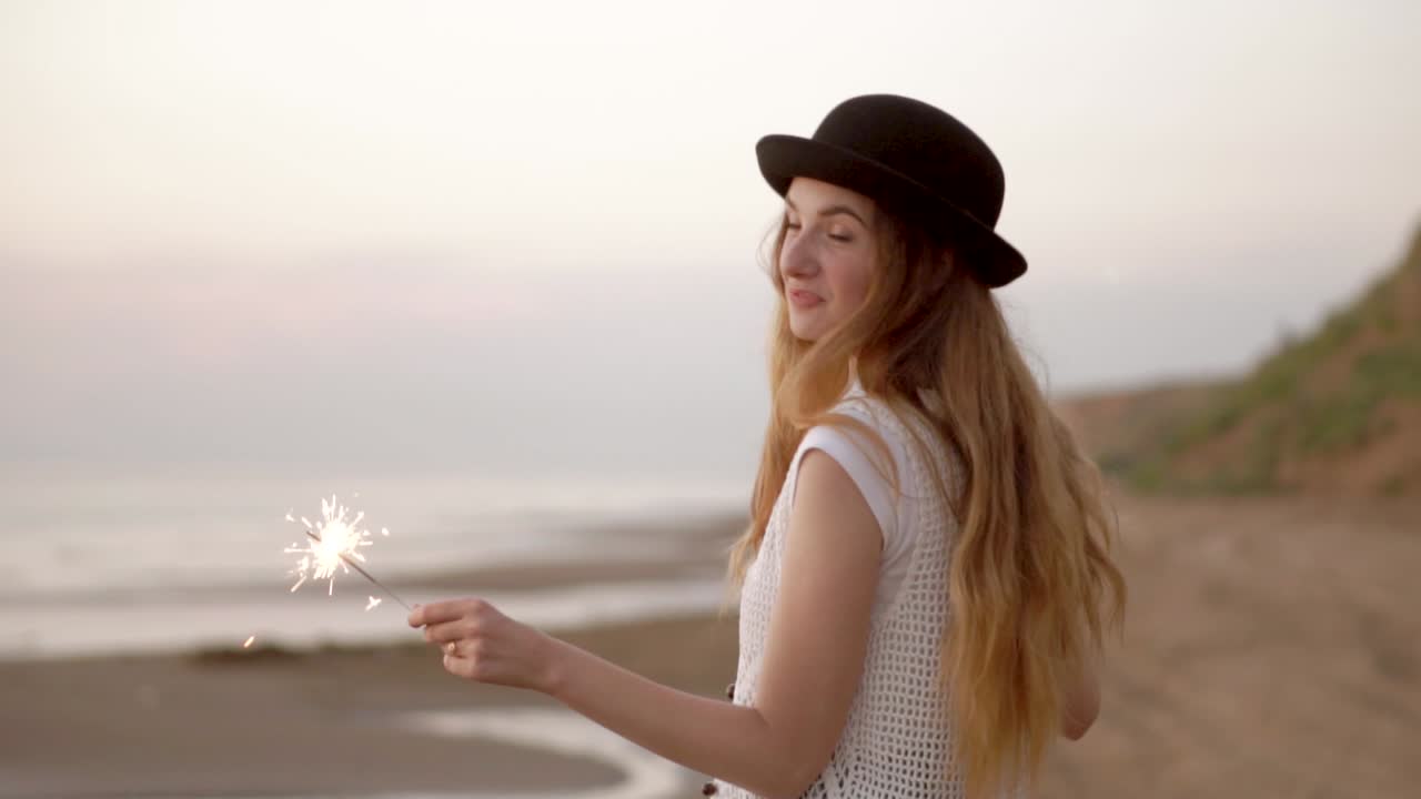 Happy Woman with Sparkler on the Beach at Sunset