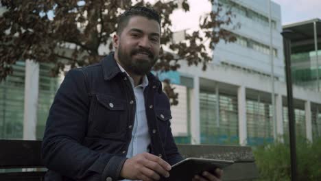 man using tablet pc and smiling at camera