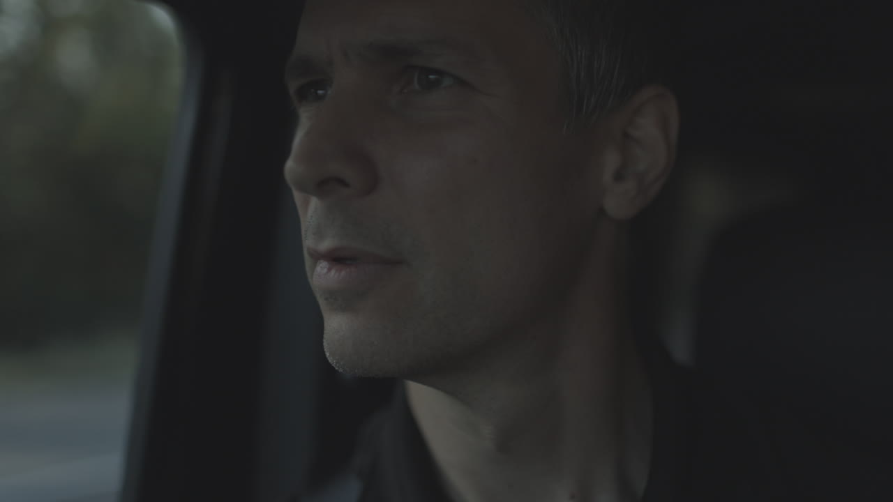 차를 타고 있는 남자가 창밖을 응시한다