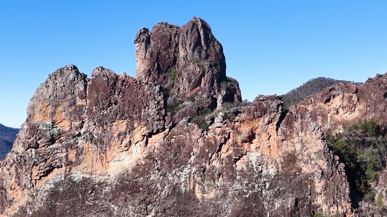 Bredt skud af gamle vulkanske tinder under en klar blå himmel i Warrumbungle, Australien