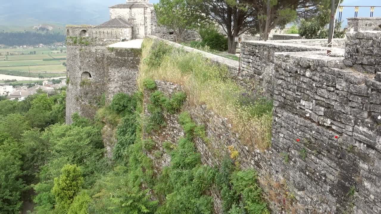 fortified walls of the old castle of ​​Gjirokaster in Albania, with flag and clock tower