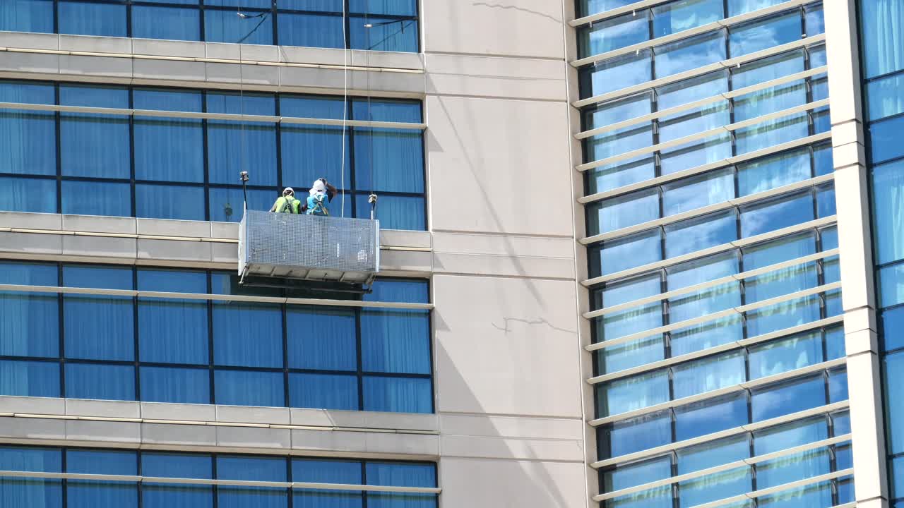 equipo de limpieza de ventanas en un edificio de gran altura