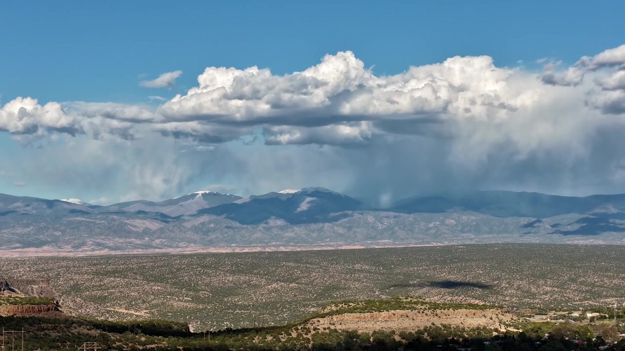 Un timelapse 4K realizzato con drone cattura nuvole dense che si addensano su una cima montuosa sud-occidentale con acquazzoni visibili. Una drammatica transizione meteorologica atmosferica mostra una vetta desertica impervia e una natura selvaggia.