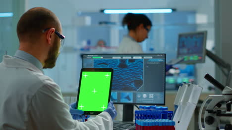 hombre con una tableta con pantalla verde en un laboratorio modernamente equipado