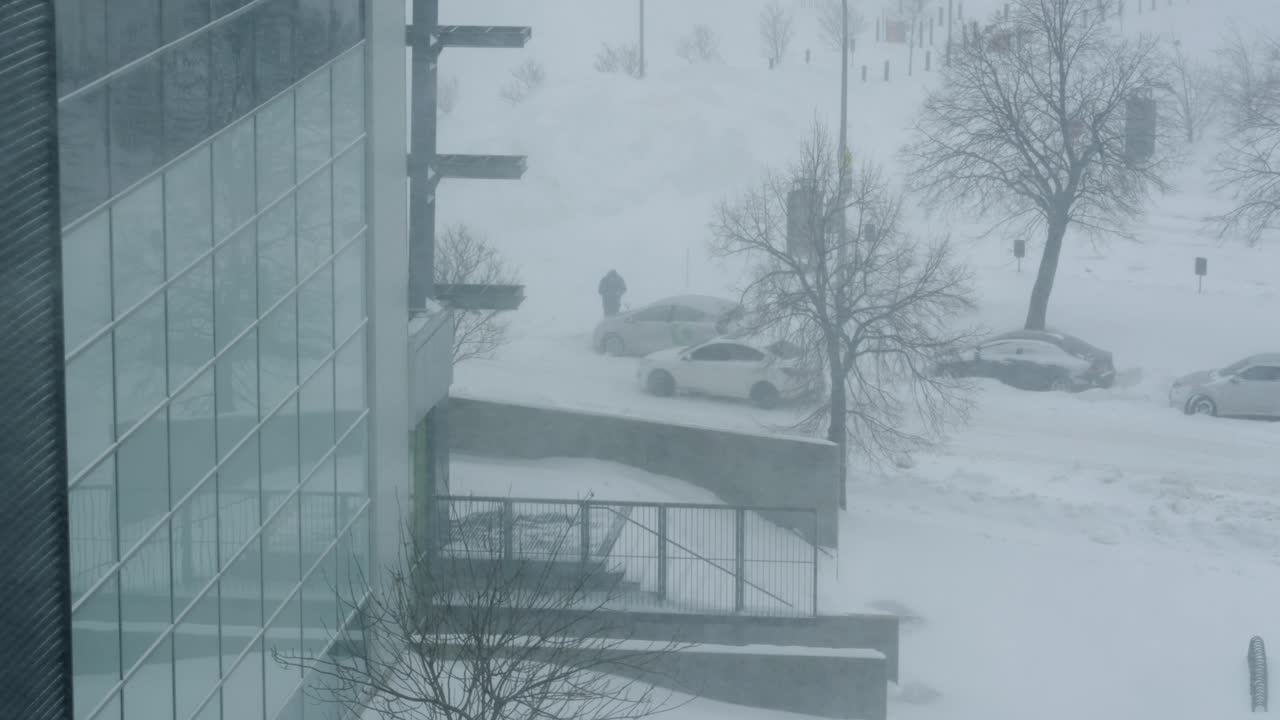 Exterior show of person looks while white car passes in heavy snow storm