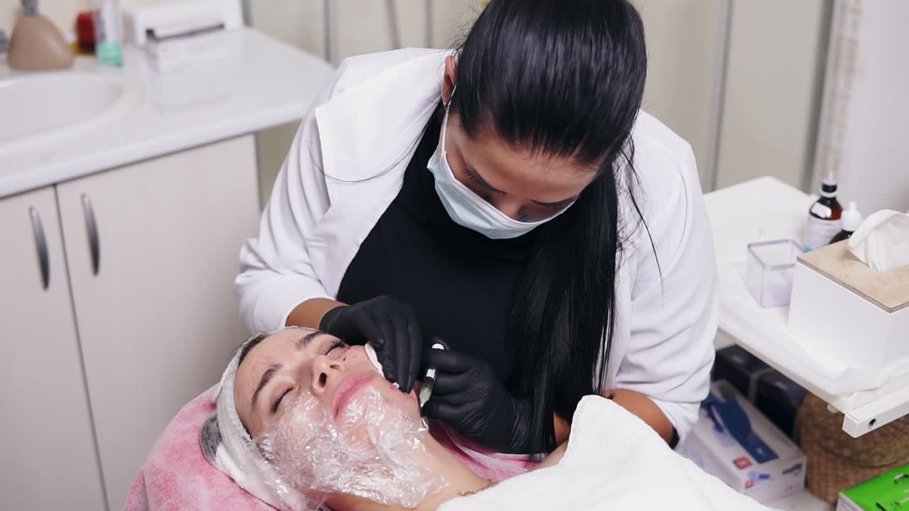 Professional cosmetologist in mask making multiple injections in woman's cheek during mesotherapy. Biorevitalization and face