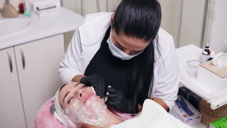 Professional-cosmetologist-in-mask-making-multiple-injections-in-woman's-cheek-during-mesotherapy.-Biorevitalization-and-face