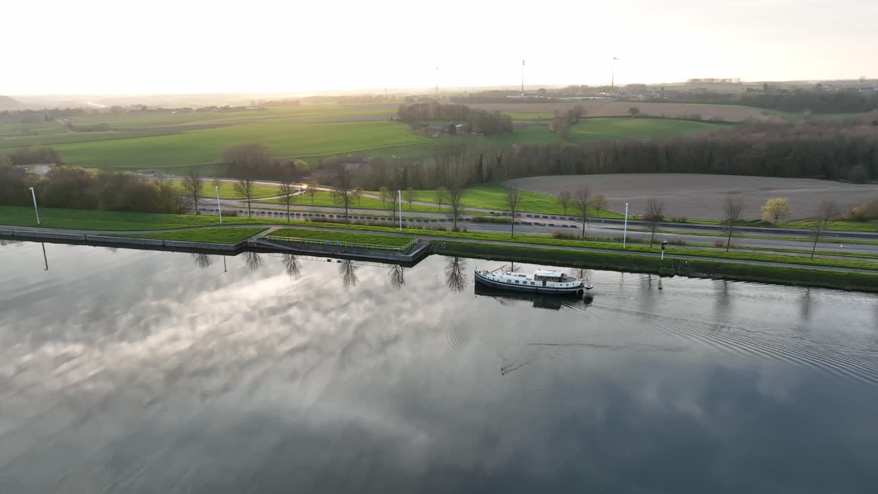 Aerial semi orbit of a boat traveling along the canal near the Strépy-Thieu boat lift in Le Roeulx at golden hour