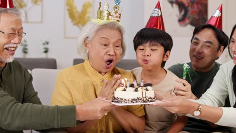 elderly family members and children enjoy a joyful birthday party with cake, candles, and laughter in a warm home setting