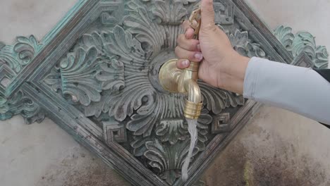 a person washing their hands at an ornate water fountain