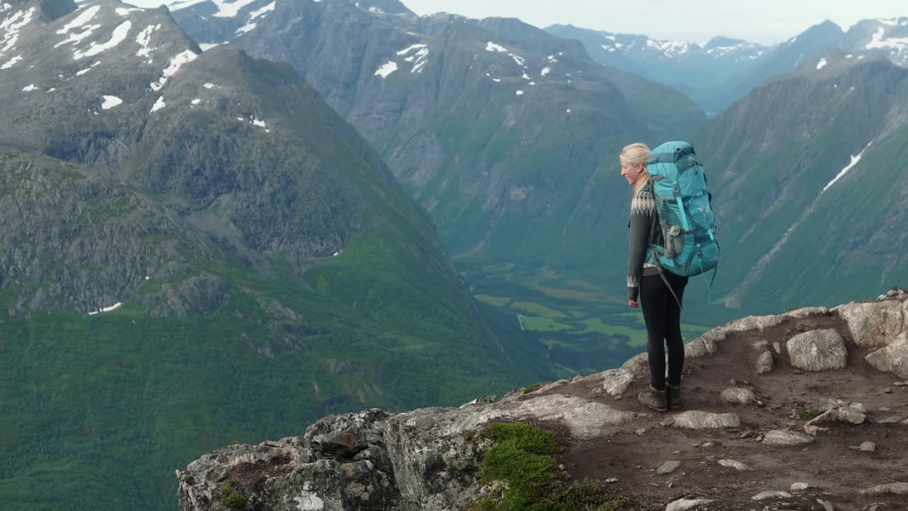 노르웨이의 멋진 산맥의 가장자리에 걸어가는 여성 하이커, 로말세겐, 산의 전망을 즐기는 소녀