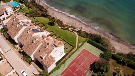 aerial birds eye view over beach side properties with tennis court in estepona, costa del sol