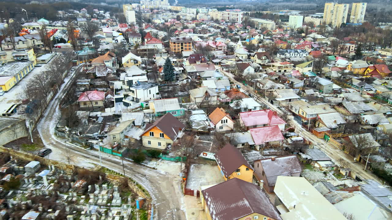 Aerial drone view of a residential distict in Chisinau, Moldova. Multiple buildings, road, cemetery on the left, Cloudy weather, bare trees, winter