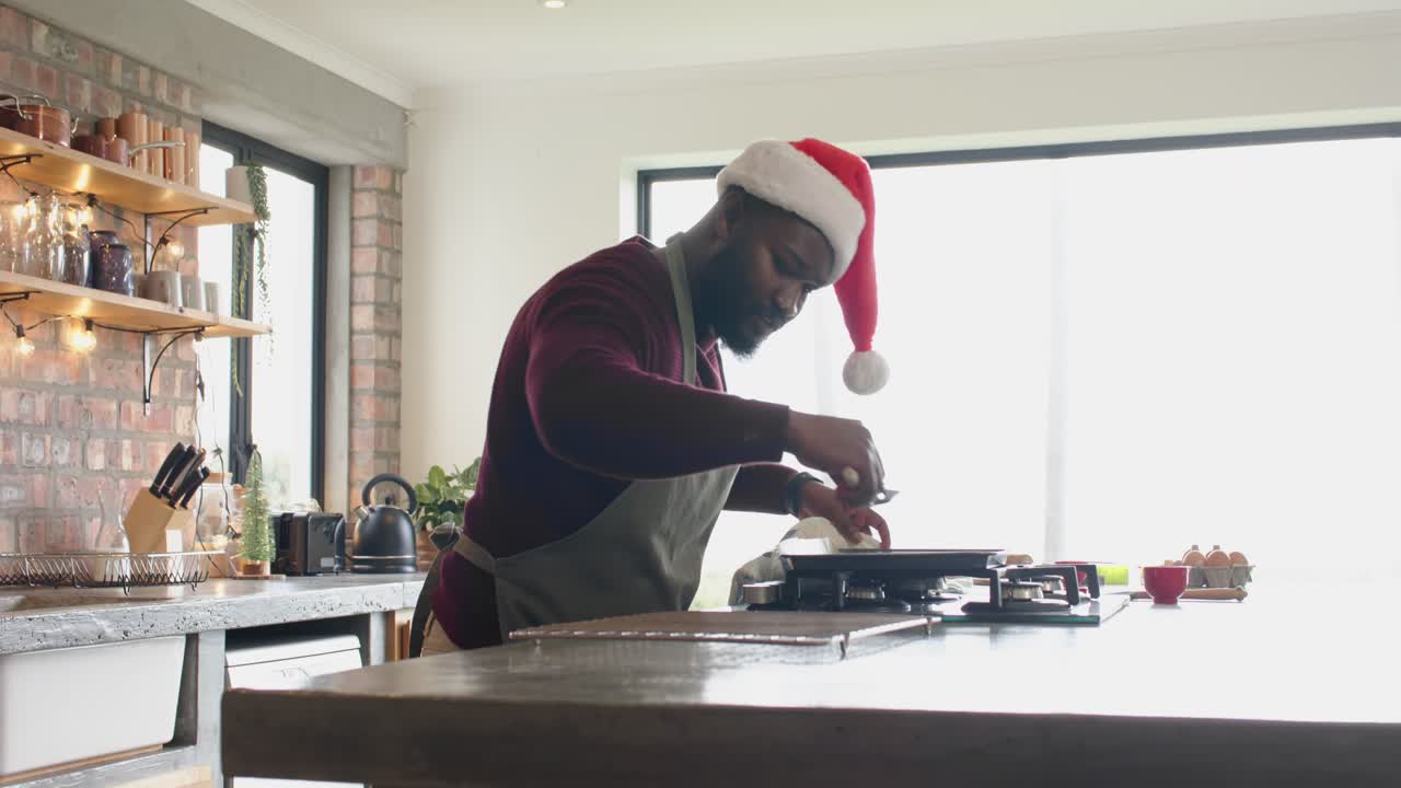African American man in Santa hat cooking omelet on kitchen island with spatula for breakfast