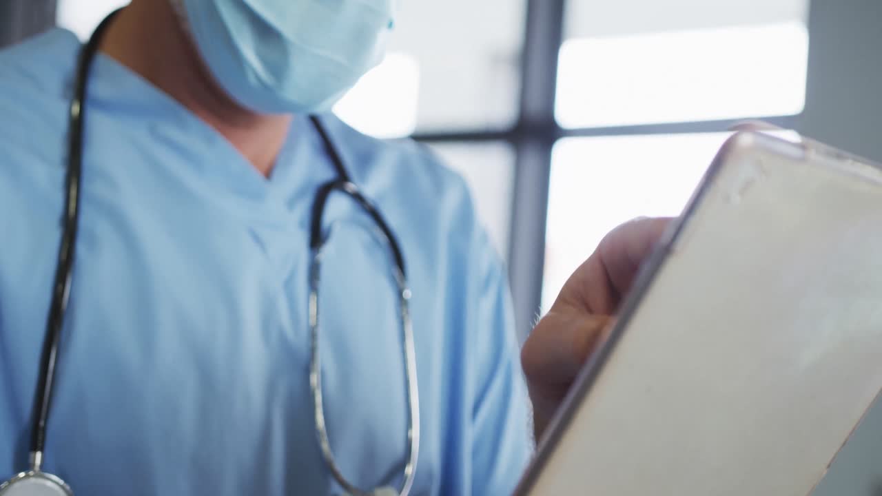 Caucasian male doctor wearing face mask using digital tablet