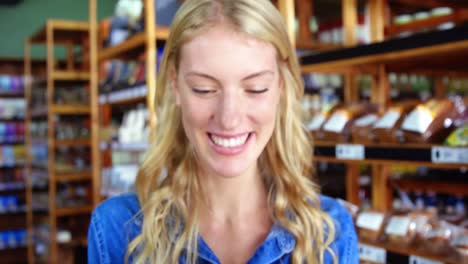 smiling female staff holding box of cherry tomato in supermarket