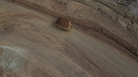 Hauler-Dump-Truck-transporting-soil-around-mine-site-in-Western-Australia,-aerial-top-down-shot