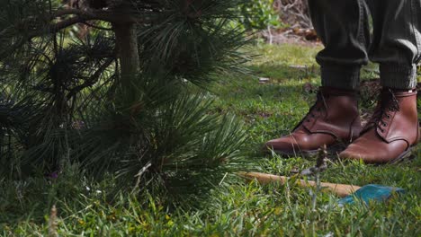 Woman-hunches-down-next-to-pine-tree-after-chopping