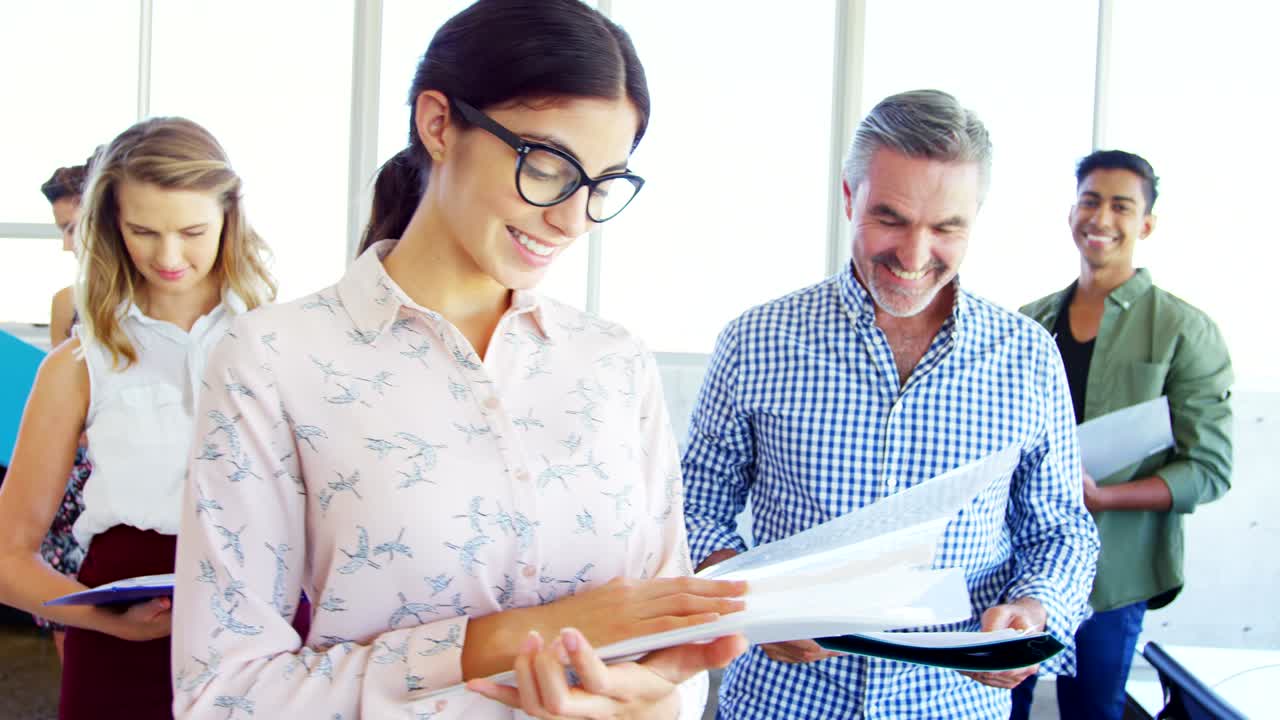 ejecutivos de negocios sonrientes de pie con el archivo en la oficina 4k