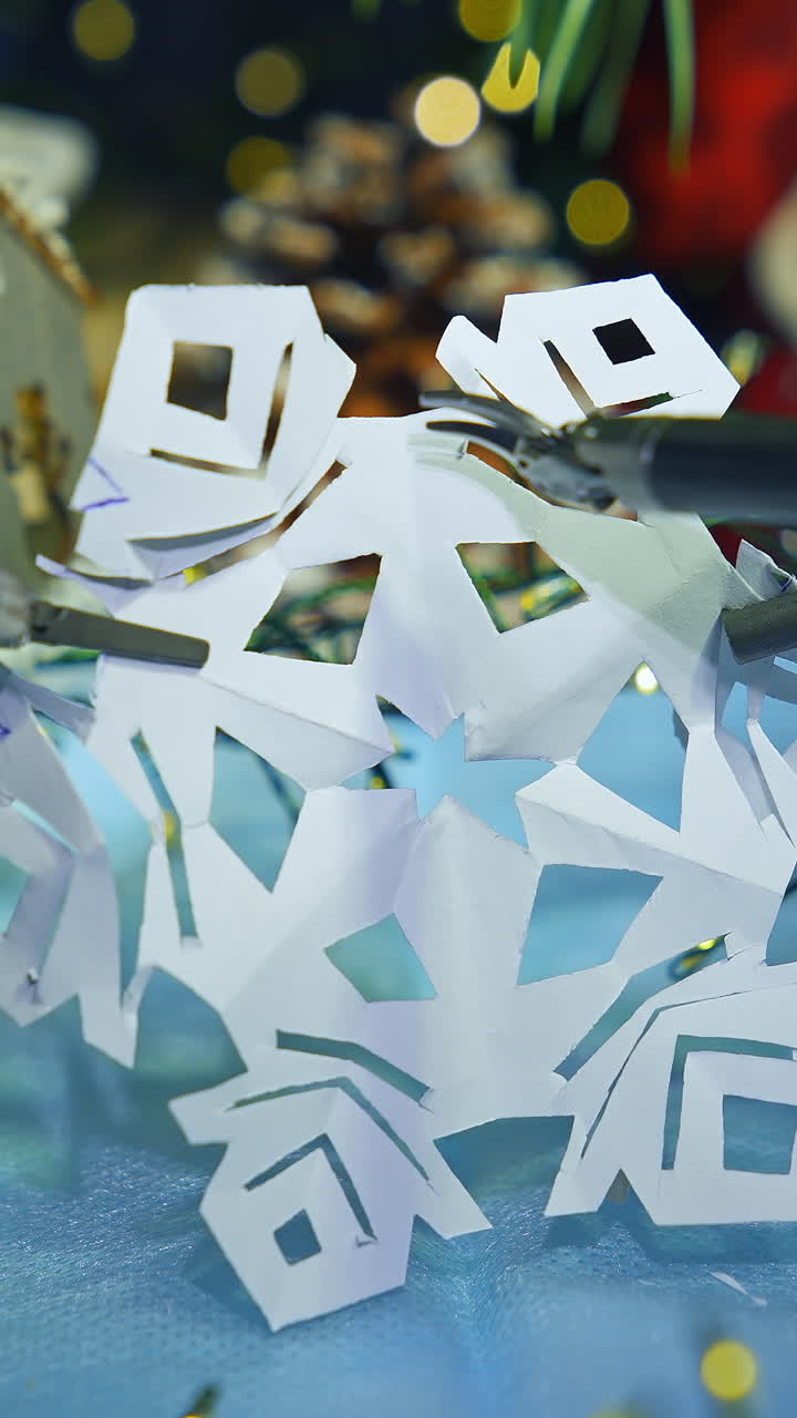 Robotic tool cutting paper snowflake. Smart robot making Christmas decorations. Modern intelligent equipment preparing for New Year. Vertical video