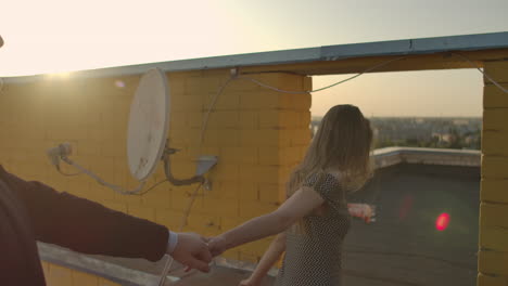 cute lovers laughing running on the roof of the building at sunset on the background of the city and hugging standing at the edge. romance and love