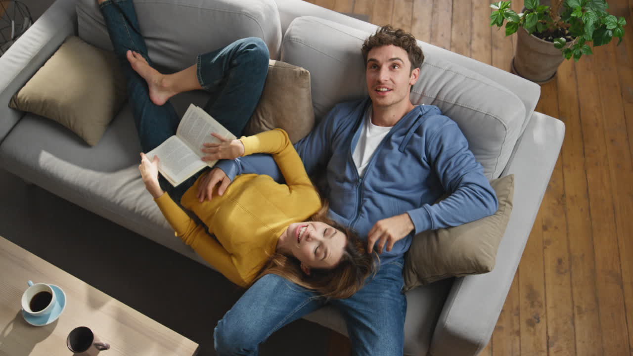 Tender pair enjoying weekend talking at couch top view. Man pointing finger