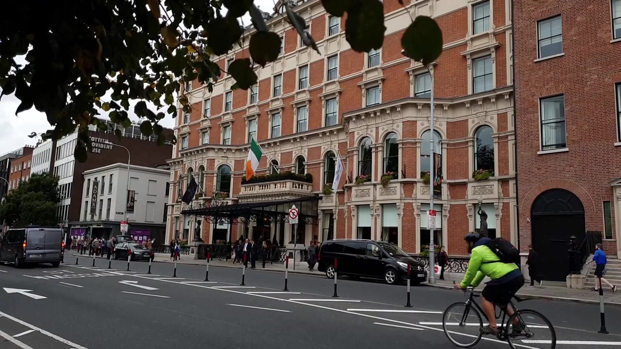 Dublino, Irlanda, fuori dall'Hotel Shelbourne, per strada, con auto e una carrozza trainata da cavalli che passano