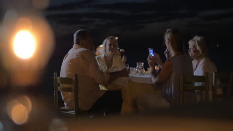 Familia-Sentada-En-Una-Mesa-Por-La-Noche-En-La-Ciudad-De-Perea,-Grecia