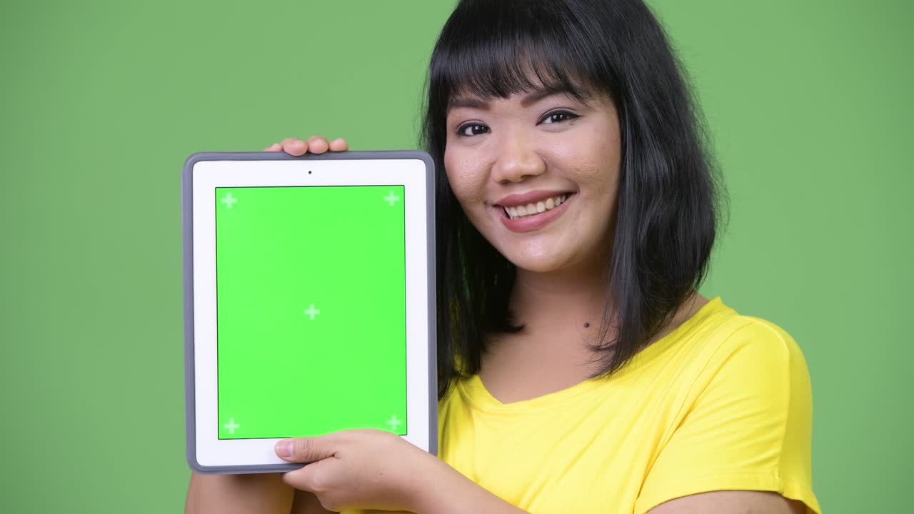 Beautiful happy Asian woman smiling while showing digital tablet