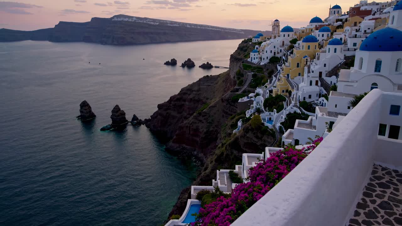 Aerial video captures a serene sunset over Santorini's coastline, highlighting white buildings