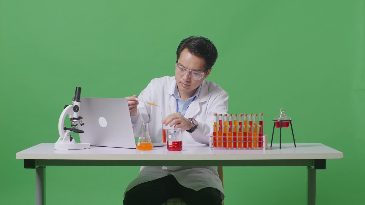 Asian Man Scientist Making Experiment With Test Tube And Screaming Goal Celebrating Typing On A Laptop On The Table With Microscope In The Green Screen Background Laboratory