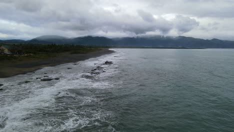 stunning ocean coastline waves crashing against rugged rocks during an overcast day at antipolo, virac, catanduanes, philippines - aerial forward shot