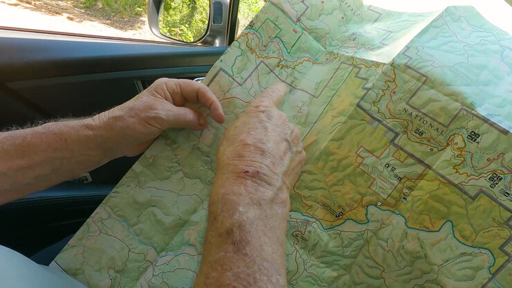Senior hiker planning route on paper map, pov