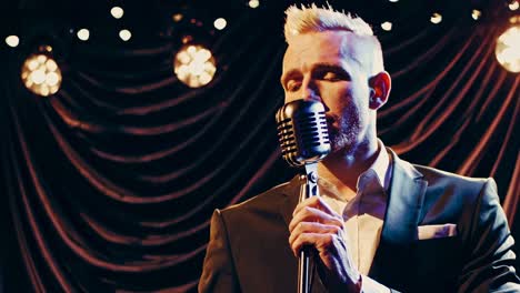 man singing into retro microphone on stage