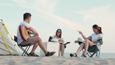 happy friend have fun playing guitar and clap in camp they smiling together in holiday on sand beach near camping tent