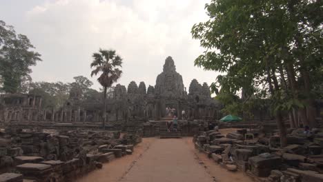 tourists walking toward the entrance of ancient bayon temple in angkor complex, point of view pov