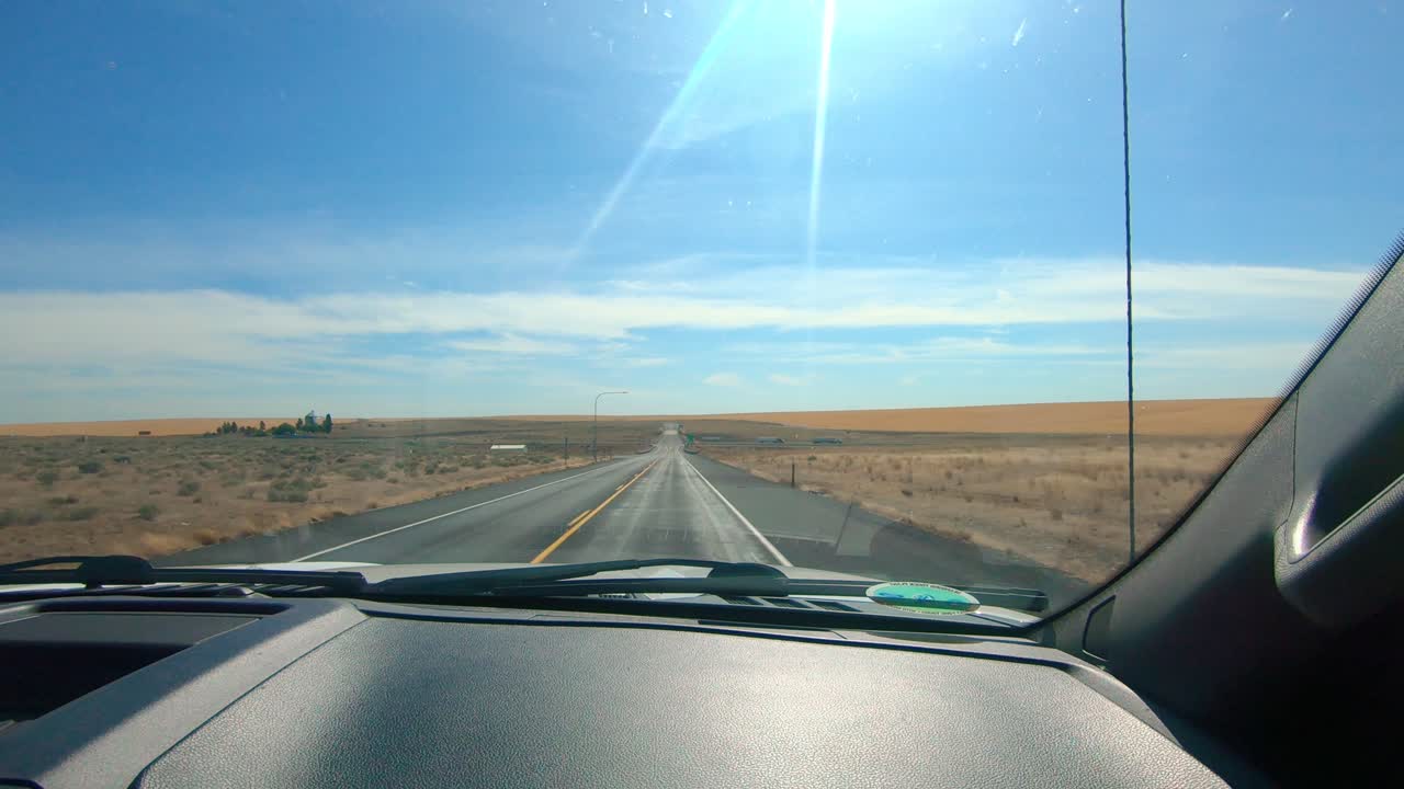 POV dal parabrezza lato passeggero mentre si guida attraverso un'area agricola dello Stato di Washington orientale.