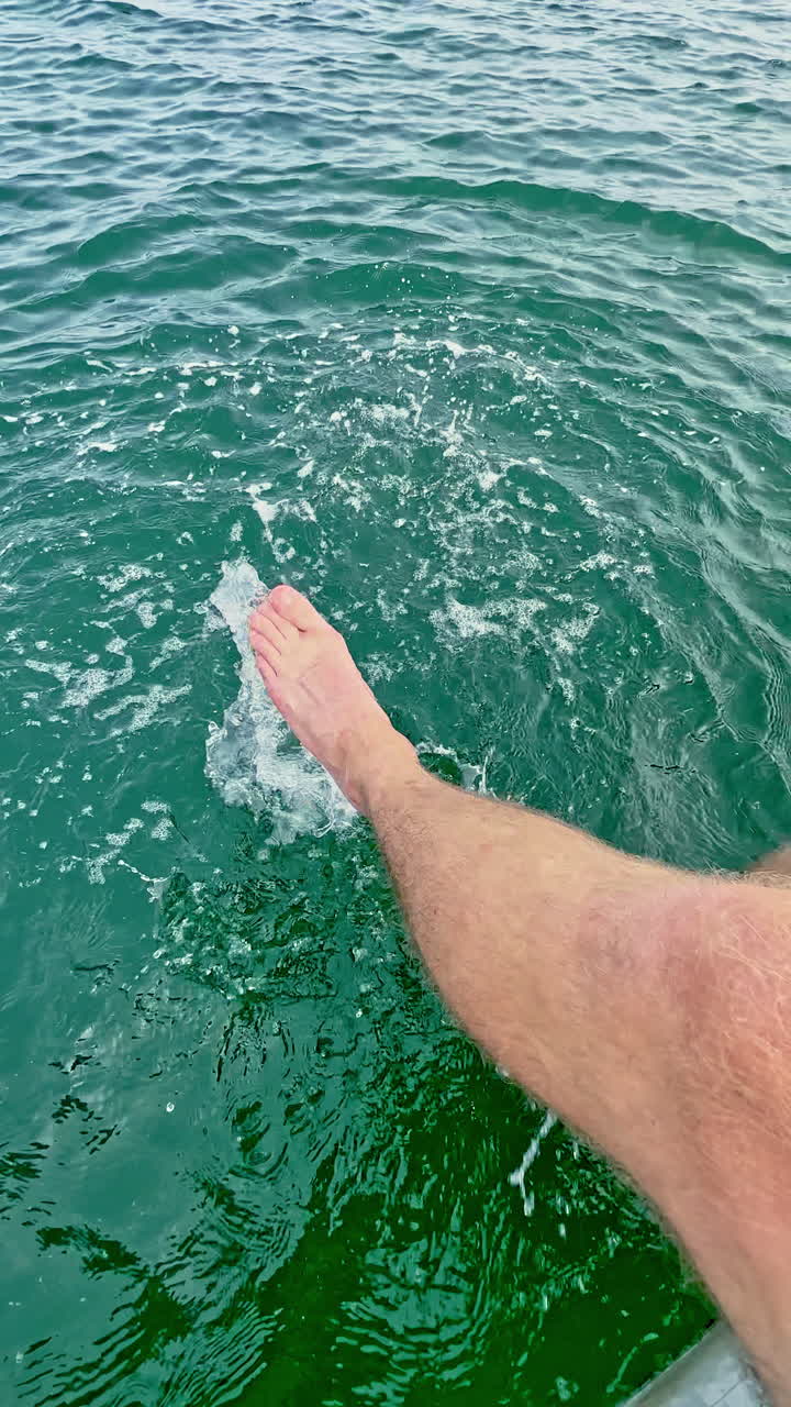 Godendosi l'acqua rinfrescante in una giornata di sole, seduti sul bordo di una barca con i piedi che schizzano tra le dolci onde.