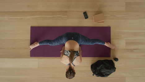 overhead view flexible yoga woman practicing wide-angle seated side bend pose enjoying healthy lifestyle exercising in fitness studio training on exercise mat