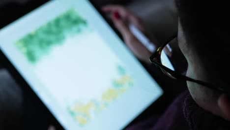 close-up of reflection in a woman's glasses as she uses a tablet