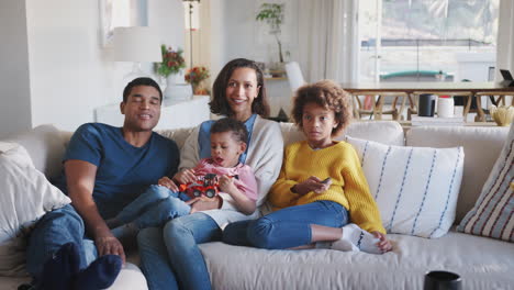 Joven-Familia-Afroamericana-Relajándose-En-El-Sofá-Viendo-La-Televisión-Juntos-En-Casa