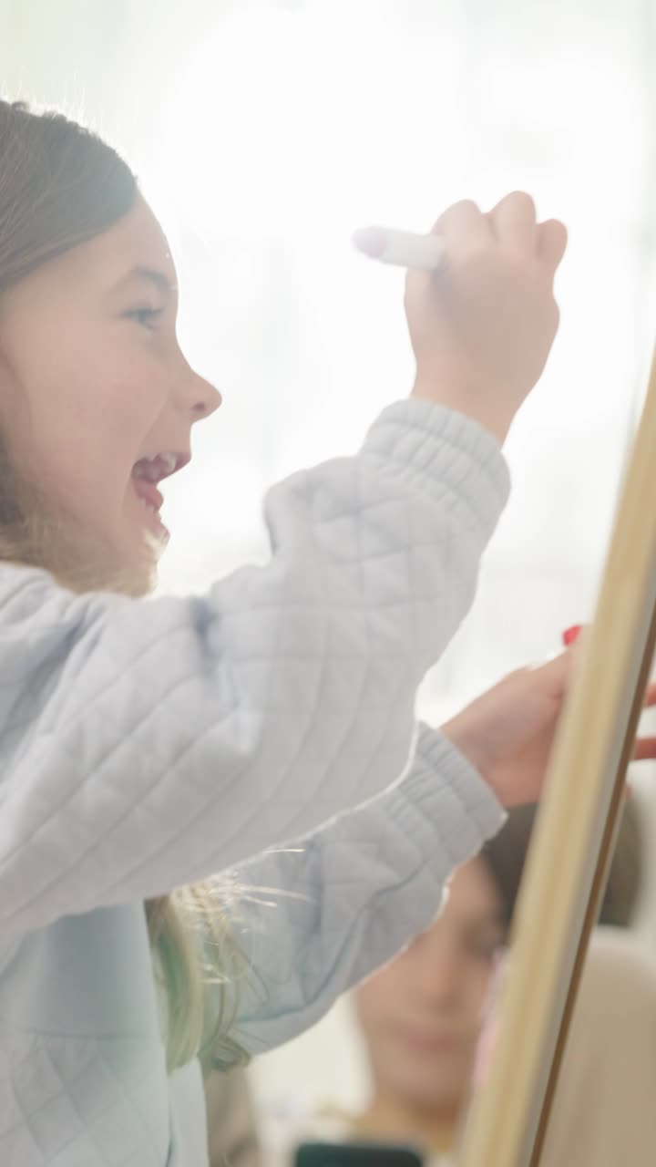 Young girl drawing on an easel or board, illuminated by bright sunlight