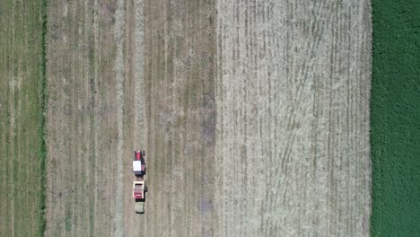 antena de arriba hacia abajo de la máquina tractora de cosecha que trabaja en la tierra agrícola con balas de heno en el entorno natural