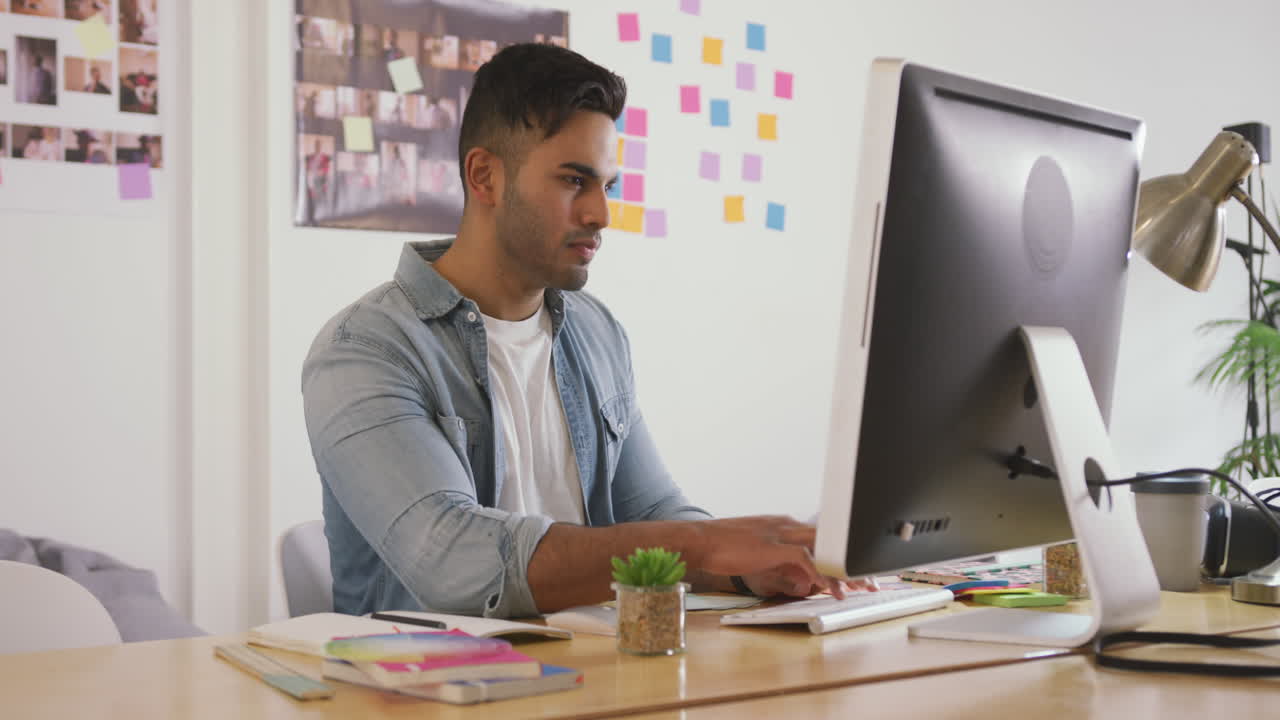 Mixed race man working on computer in creative office